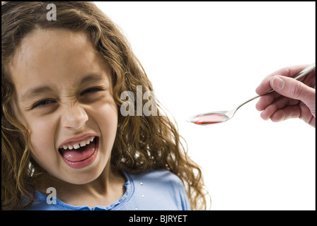 Giovane ragazza tenendo un cucchiaio di medicina Foto Stock