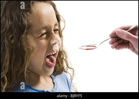 Giovane ragazza tenendo un cucchiaio di medicina Foto Stock