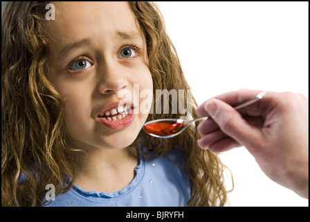 Giovane ragazza tenendo un cucchiaio di medicina Foto Stock