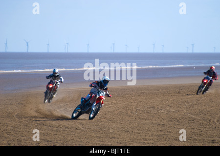 Moto Racing di sabbia sulla spiaggia con le turbine eoliche in background sul mare, Mablethorpe, Lincolnshire, England, Regno Unito Foto Stock