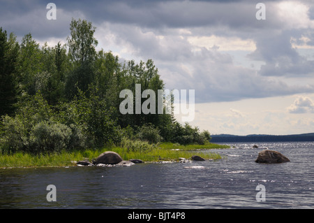 La bella immagine di Karelian foresta a bordo di un lago, e alcuni enorme masso in questo lago Foto Stock