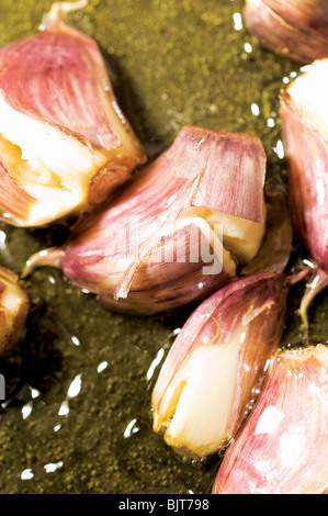 Spicchi d'aglio fritti in olio d'oliva caldo in padella di ghisa. Ingrediente biologico prodotto dal mercato regionale locale in Alvor Algarve Portogallo Foto Stock