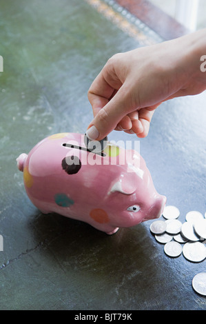 Persona messa moneta nel salvadanaio Foto Stock