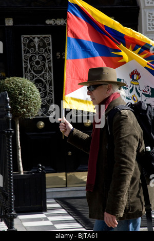 Un sostenitore porta un tibetano bandiera nazionale lungo Portland Place in central London REGNO UNITO durante un Tibet libertà Marzo Foto Stock