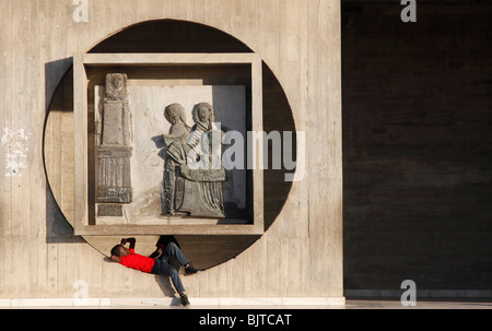 Da giovane si rilassa sotto una scultura al di fuori della cattedrale. La chiesa di Nostra Signora di Fatima. ( Igreja da Nossa Senhora de Fatimia). Foto Stock