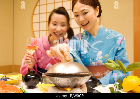 Donne abbigliate in yukatas seduti a mangiare un pasto Foto Stock