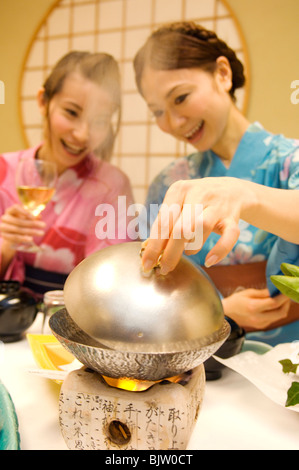 Donne abbigliate in yukatas seduti a mangiare un pasto Foto Stock