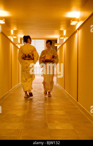 Due donne che indossano yukata passando a vicenda nel corridoio di un health spa Foto Stock