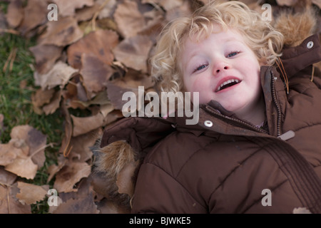 Ragazza giovane sdraiato sulle foglie Foto Stock