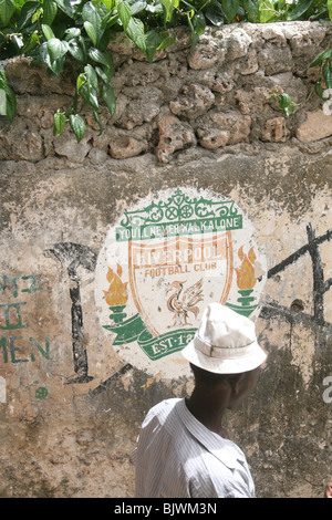 Un uomo cammina passato a Liverpool football club segno dipinto sul muro nella città di Lamu, Kenya, Africa orientale Foto Stock