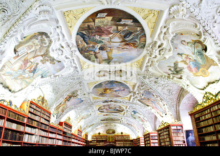 PRAGA, Repubblica Ceca: L'interno mozzafiato della Biblioteca Strahov, situata all'interno del Monastero di Strahov a Praga. Questa immagine cattura l'opulento design barocco della biblioteca, probabilmente concentrandosi sulla sala filosofica. La sala presenta scaffali in noce da pavimento a soffitto pieni di antichi tomi, uno splendido soffitto affrescato raffigurante scene allegoriche di conoscenza umana e intricati dettagli architettonici che mettono in mostra il massimo dell'artigianato e della visione artistica del XVIII secolo. Foto Stock