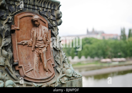 Ponte Carlo Statua dei Santi Cirillo e Metodio Bronzo sollievo Praga Repubblica Ceca | PRAGA, Repubblica Ceca - Un rilievo in bronzo intemprato sulla Statua dei Santi Cirillo e Metodio raffigura una figura slava inginocchiata, uno dei numerosi pannelli che illustrano i popoli evangelizzati dai due missionari bizantini del IX secolo, con il castello di Praga visibile oltre la Moldava. Il gruppo scultoreo, di Karel Dvořák, fu installato tra il 1928 e il 1938 sul Ponte Carlo, completato nel 1402. Foto Stock