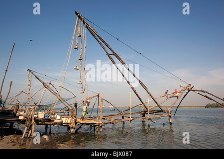 India Kerala, Kochi, Fort Cochin, uomini al lavoro su pesca cinesi Net Foto Stock