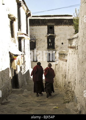 Due monaci a piedi lungo gli stretti camminamenti presso il monastero di Drepung a Lhasa, in Tibet Foto Stock