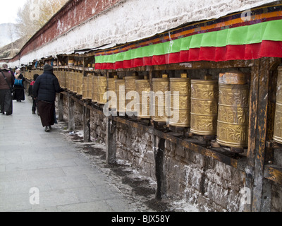 Pellegrini spin ruote della preghiera mentre si cammina intorno al palazzo del Potala a Lhasa, in Tibet. Foto Stock