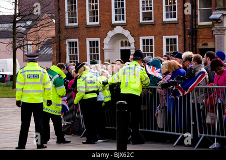 Aiuto della polizia una signora anziana da dietro la folla barriera nel derby al Giovedì Santo celebrazioni e prendere il suo di sedersi. Foto Stock