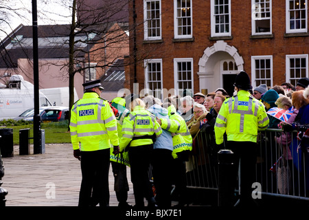 Aiuto della polizia una signora anziana da dietro la folla barriera nel derby al Giovedì Santo celebrazioni e prendere il suo di sedersi. Foto Stock