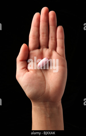 Una femmina di donna di mano che tiene una pillola nel palmo della sua mano Foto Stock