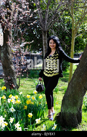 Giovane donna graziosa a piedi attraverso il parco circondato dalla molla fiore e i fiori southsea England Regno Unito Foto Stock