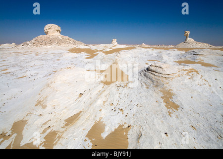 Inselburgs con circostante sabbia ondulata, in condizioni di luce solare intensa,Bianco Deserto, Farafra, Egitto, Nord Africa Foto Stock