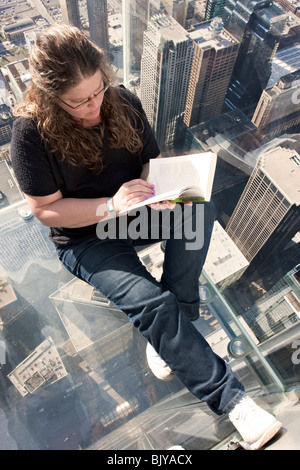 La battuta - Donna lettura al ponte di osservazione (lo skydeck) sulla parte superiore della Willis (ex) Sears Tower a Chicago, Illinois, Stati Uniti d'America Foto Stock