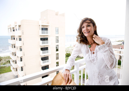 Di mezza età donna sorridente sul balcone del condominio sul fronte spiaggia Foto Stock