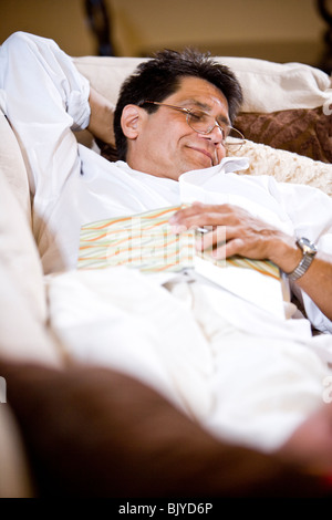 Uomo di mezza età disteso che dorme sul divano Foto Stock