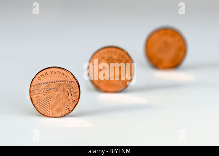 Tre un penny pezzi in linea diagonale contro uno sfondo bianco con la seconda e la terza delle monete in euro al di fuori della messa a fuoco Foto Stock
