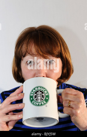Donna di bere il caffè dal grande Starbucks mug Foto Stock