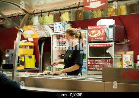 Giovane donna serve piatti fast food al festival rock Foto Stock