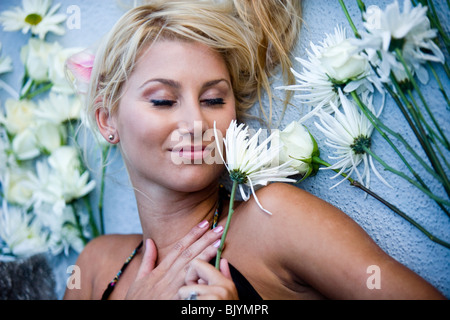 Vista da sopra della giovane donna bionda sdraiato circondato da fiori Foto Stock