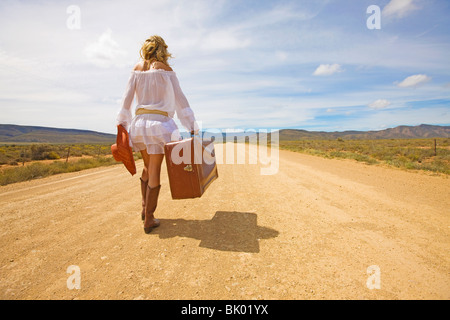 Donna solitaria sulla strada del deserto Foto Stock