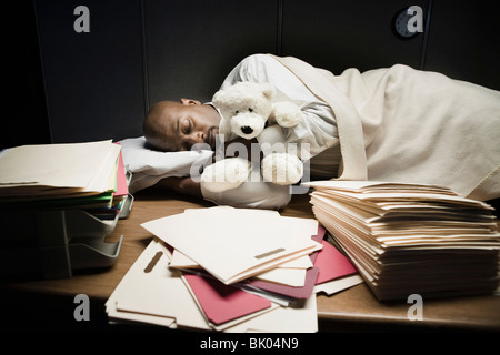 Uomo con animali impagliati dormire a scrivania Foto Stock