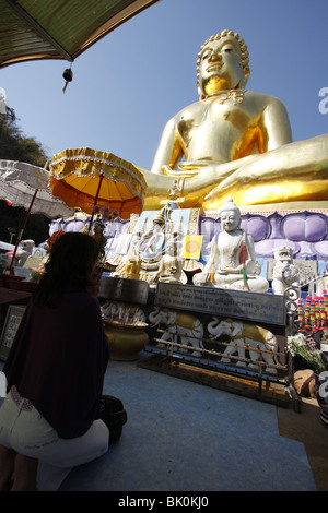 Una donna che prega di fronte a un gigante Buddha d'oro a Sop Ruak, Il Triangolo d'oro, dal Mekong nella Tailandia del Nord Foto Stock