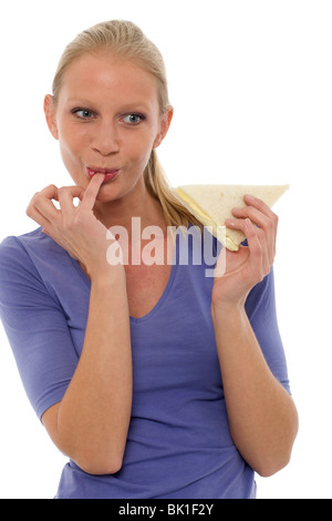 Ritratto di una giovane donna caucasica con il dito in bocca di mangiare un panino Foto Stock