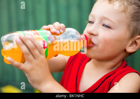 Little Boy bere malsano di soda in bottiglia Foto Stock