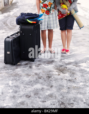 Matura in piedi nella neve con le valigie Foto Stock