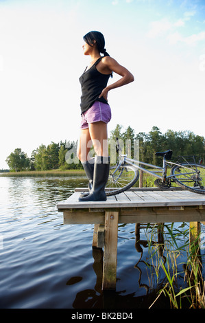 Donna con bici, alla fine di un dock Foto Stock