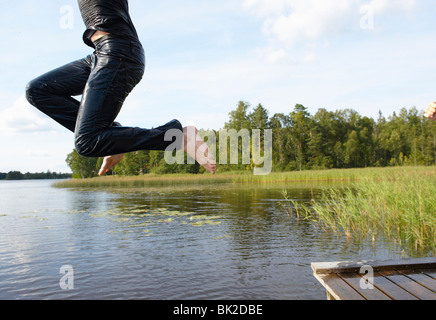 Uomo di saltare nel lago con le sue vesti Foto Stock