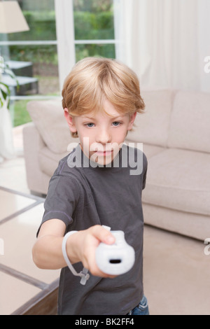 Un ragazzo puntando una console per videogiochi alla fotocamera Foto Stock