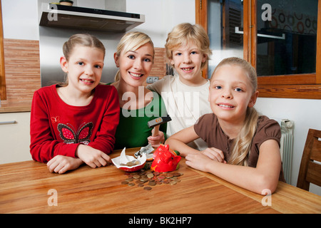 Famiglia smash aprire un salvadanaio Foto Stock