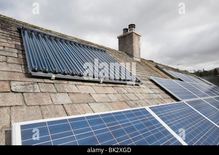 Energia solare fotovoltaica di generazione di energia elettrica e di pannelli solare di acqua calda pannelli su un tetto di casa a Ambleside, Cumbria, Regno Unito. Foto Stock