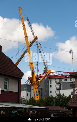 Gru a torre crollata caduto sul tetto del condominio essendo sollevata da un altro gru Foto Stock