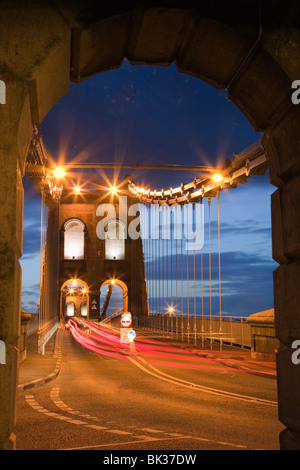 Vista lungo la A5 strada notturna attraverso la sospensione di Menai Bridge, da Thomas Telford in 1825, Bangor, Gwynedd, il Galles del Nord Foto Stock