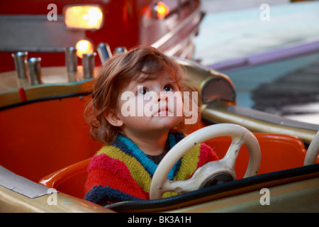 22 mesi ragazza all'interno di un incendio auto merry-go-round in movimento Foto Stock