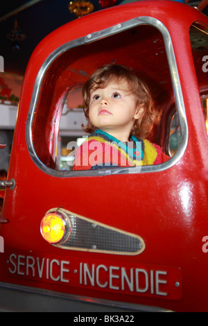 22 mesi ragazza all'interno di un incendio auto merry-go-round in movimento Foto Stock