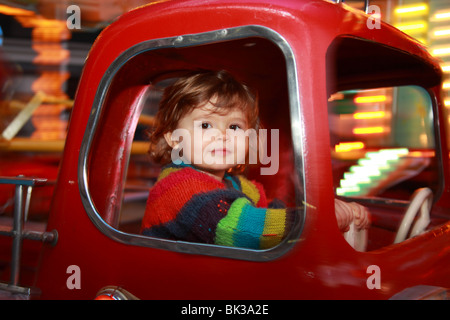 22 mesi ragazza all'interno di un incendio auto merry-go-round in movimento Foto Stock