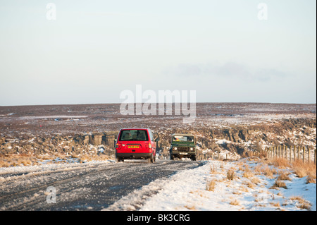 Vehicles on snow covered road, Peak District, Derbyshire, UK Foto Stock