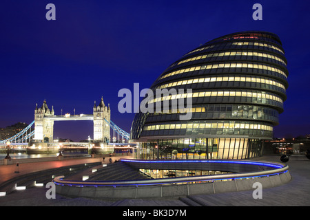 Più di Londra, il Municipio e il Tower Bridge di notte. New London lo sviluppo delle città sulle rive del fiume Tamigi. Foto Stock