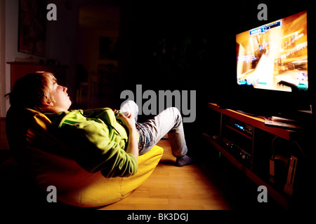 Il ragazzo, 15 anni, giocando un online xbox. gioco utilizzando un grande schermo piatto Foto Stock